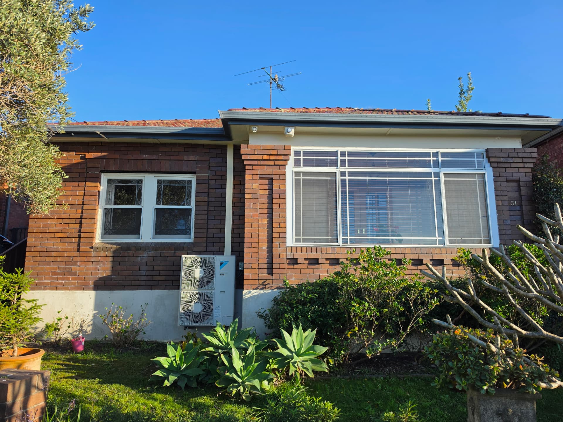 Single-storey red brick home photographed before pressure cleaning