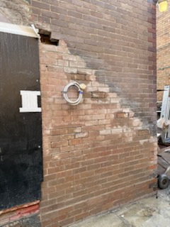 Close view of deteriorated mortar and brickwork beside a dark doorway