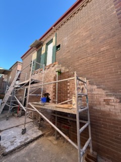 Scaffolding set up along a tall brick wall for restoration access