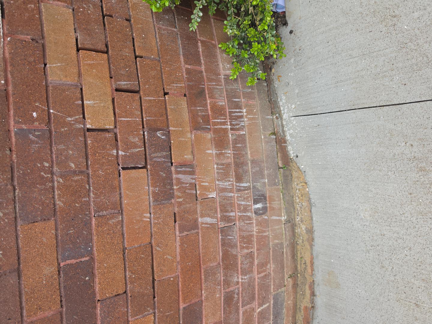 Close view of deteriorated mortar in red brickwork beside paving